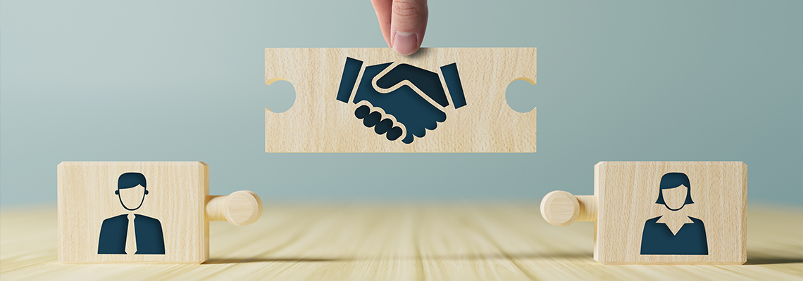 The hand holds wooden wooden blocks with icons of a woman and a man