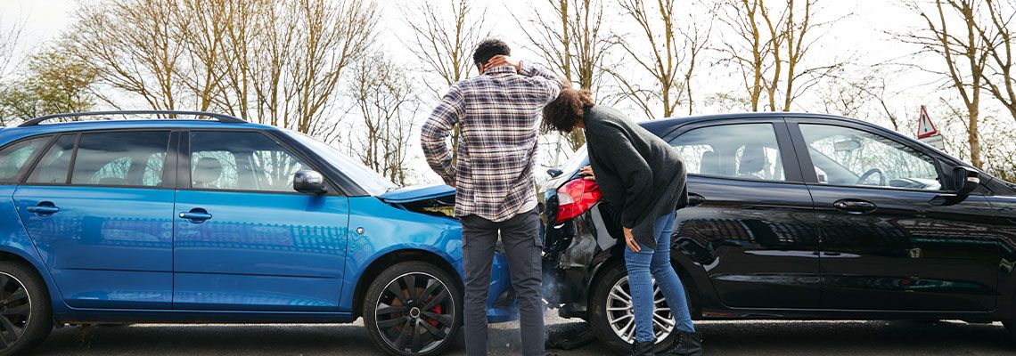 Driver inspecting damage after car accident