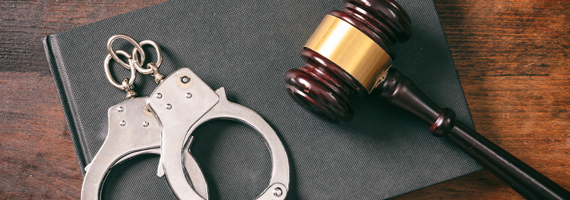 Handcuffs, gavel on book on a wooden background