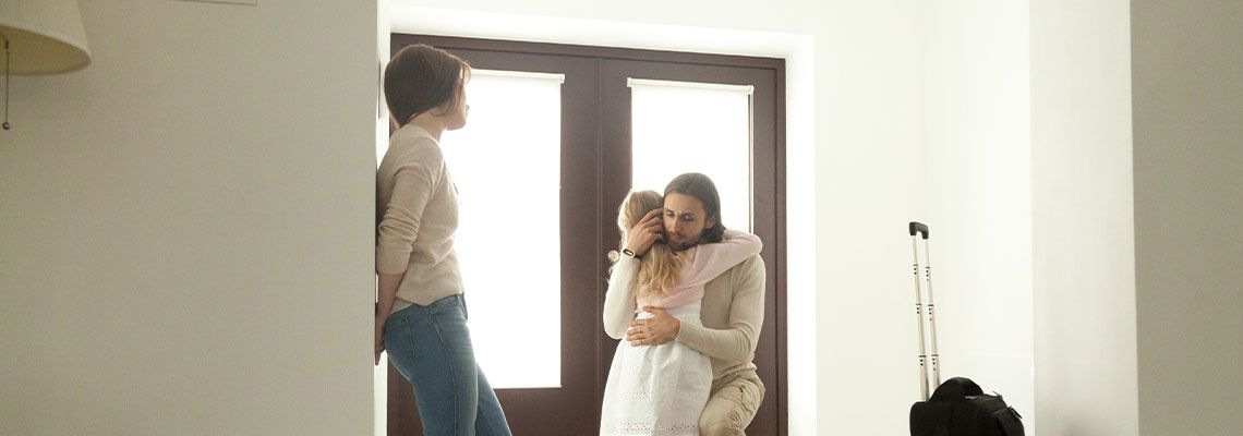 Little girl hugging father, who is leaving her with mother