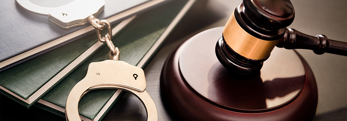 Gavel and handcuffs on table with book