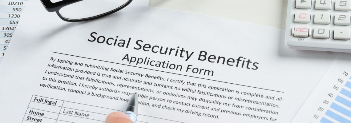 Hand Holding Pen Over Social Security Benefits Form