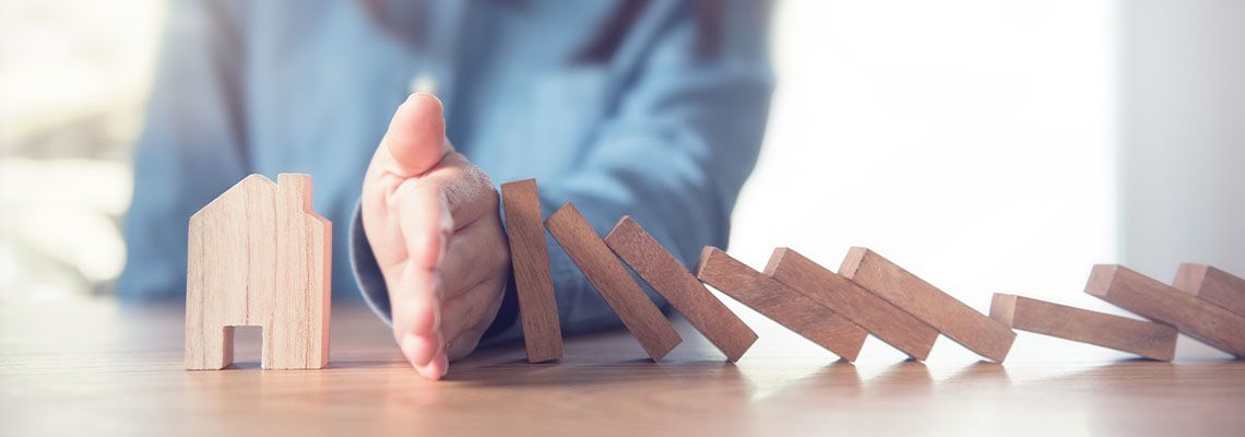 Women stopping wooden blocks from falling into house model