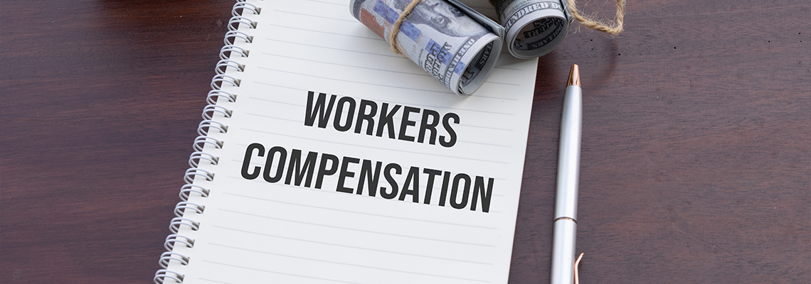 A notebook labeled 'Workers Compensation' accompanied by cash