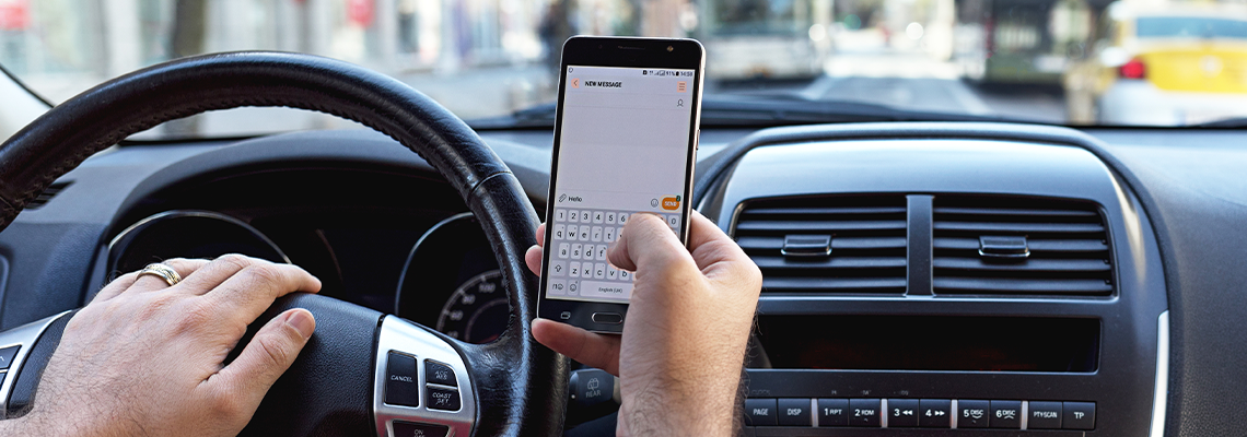Man sending message from a smartphone while driving a car