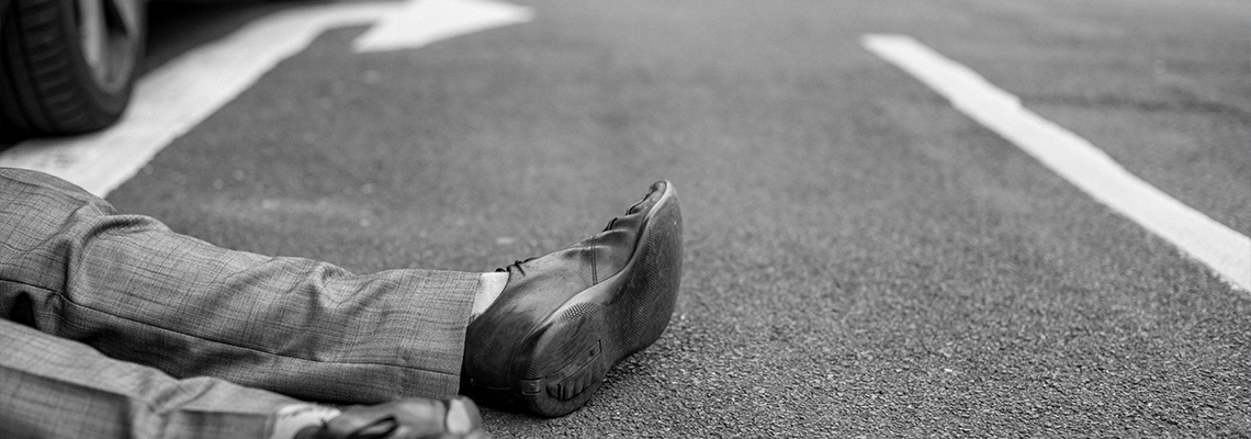 Person lying on the ground after a car accident