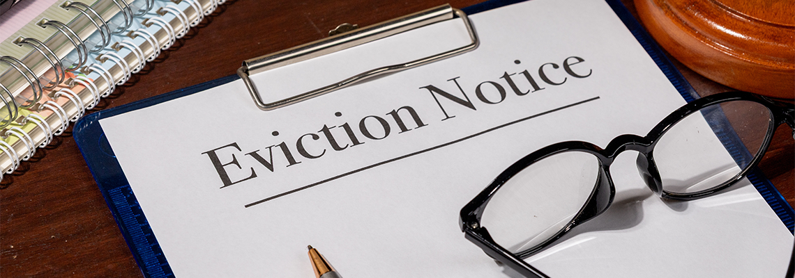 An eviction notice document lies beside a gavel on a wooden desk