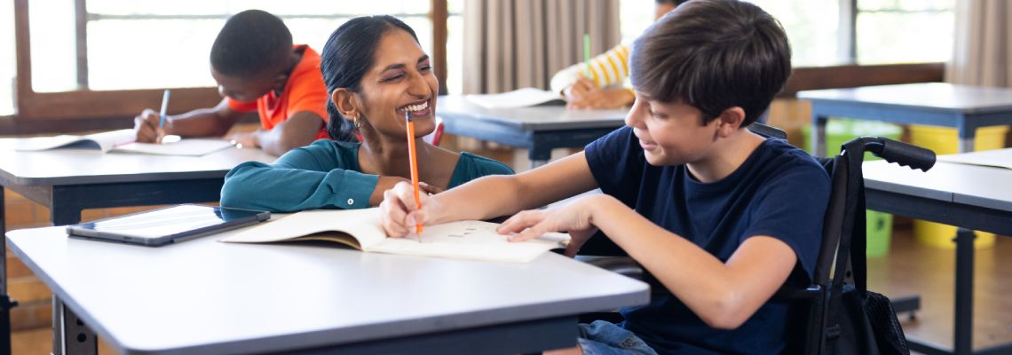 Teacher helping disabled student in class