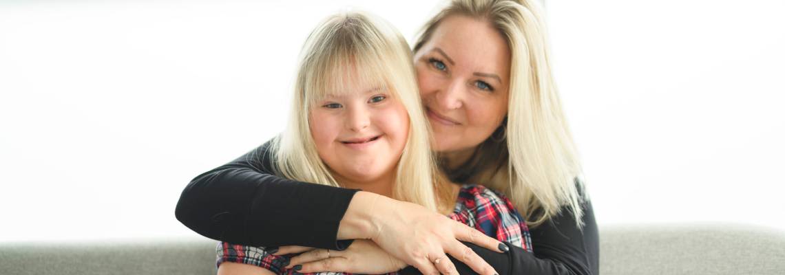 Mother and sweet down syndrome daughter girl at home sofa