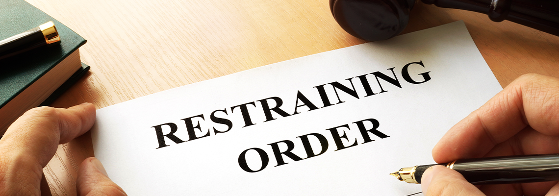 Document with the name restraining order and gavel on table
