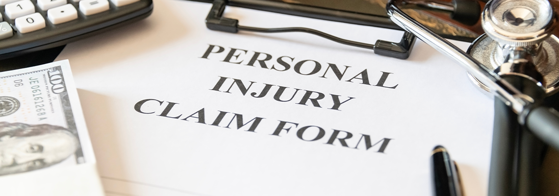 Close-up of a personal injury claim form with a stethoscope, calculator, and cash