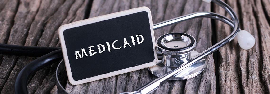 Medicine concept. Blackboard with word MEDICAID and stethoscope