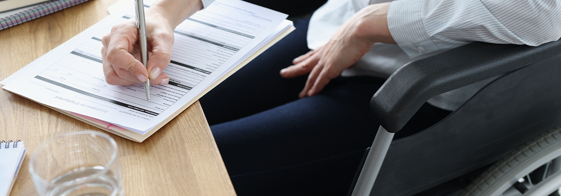 Disabled woman in wheelchair filling out application for employment closeup