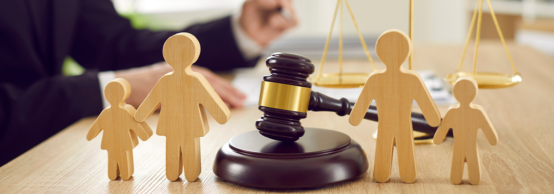 Gavel, sound block and little wooden figures of parents and children placed on desk