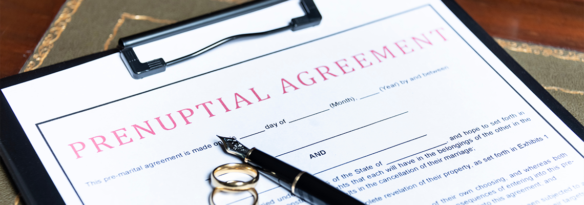 Prenuptial agreement form with wedding rings and a fountain pen on table