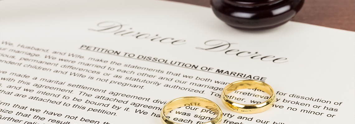 Wooden judge gavel, golden rings, and divorce decree