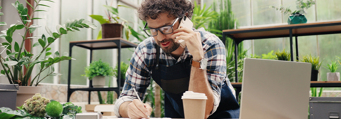Happy Caucasian businessman talking on cellphone while standing in apron