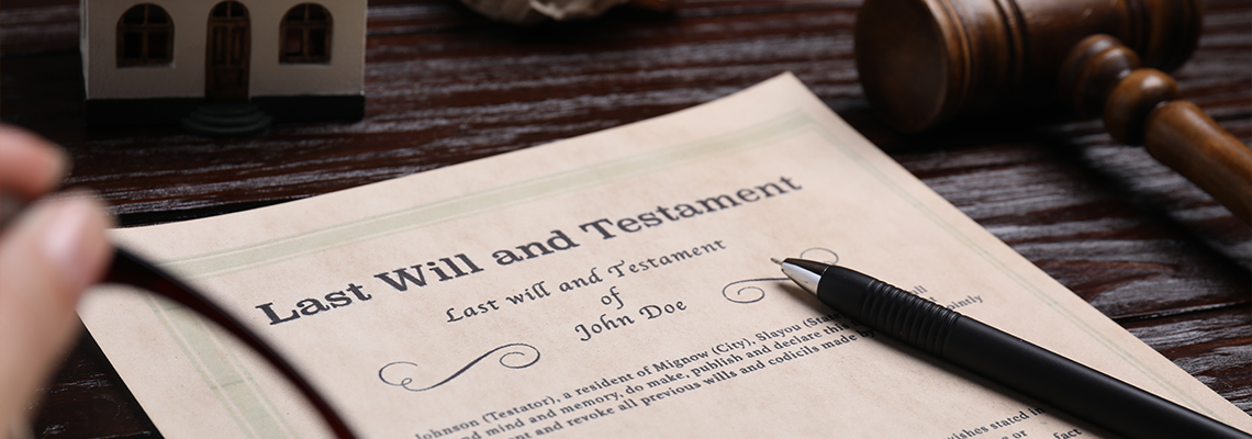 Last will and testament near house model and gavel on wooden table