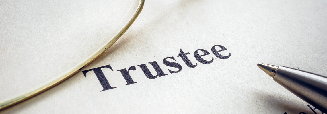 Word trustee near glasses and a pen
