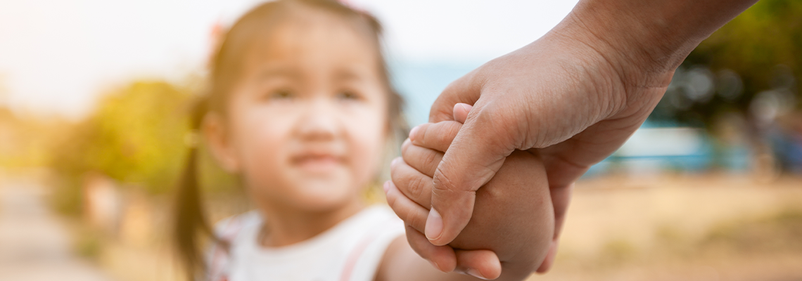 Parent and asian child girl holding hand together with love and care