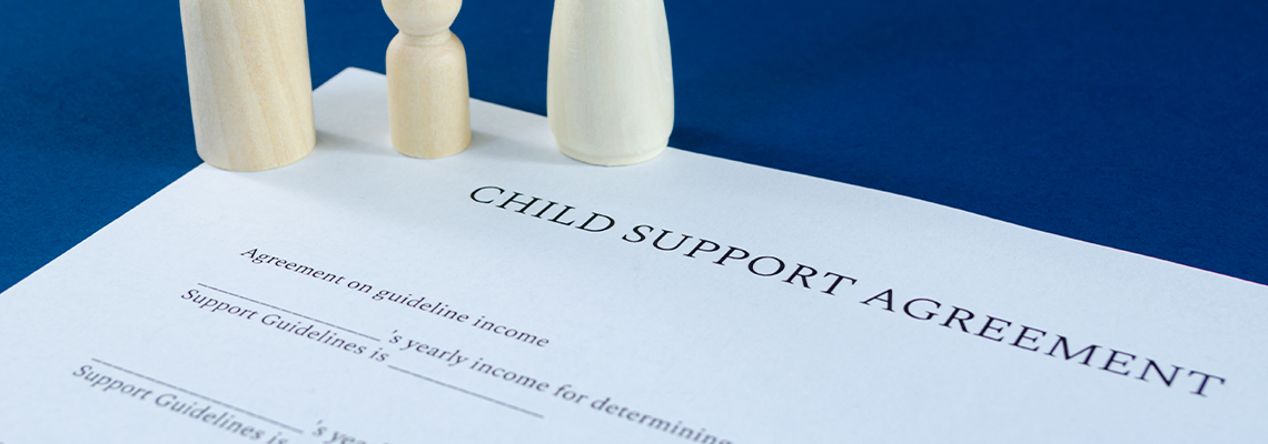 Printed child support agreement with man, woman and child wooden figures