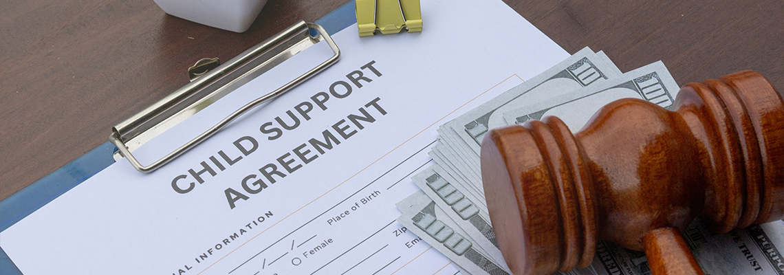 Child support agreement paper on a desk with cash, a gavel, and a calculator