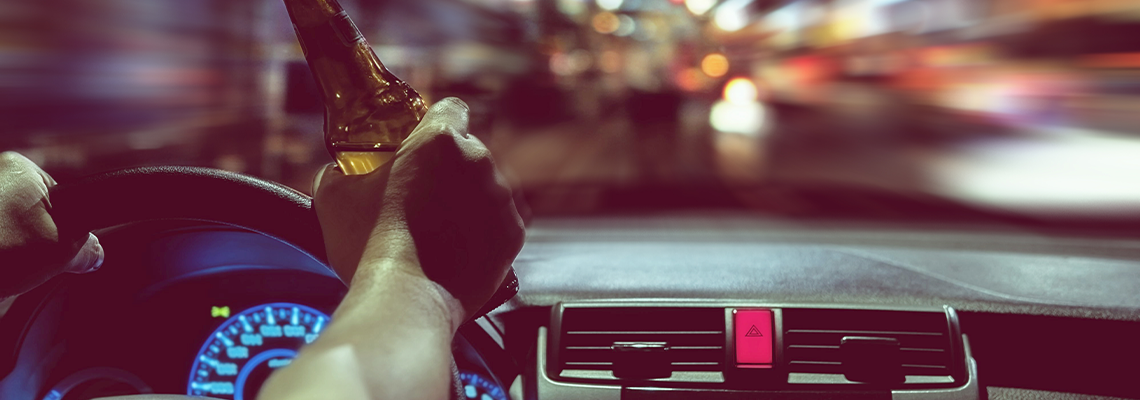Man drink beer while driving at night in the city dangerously