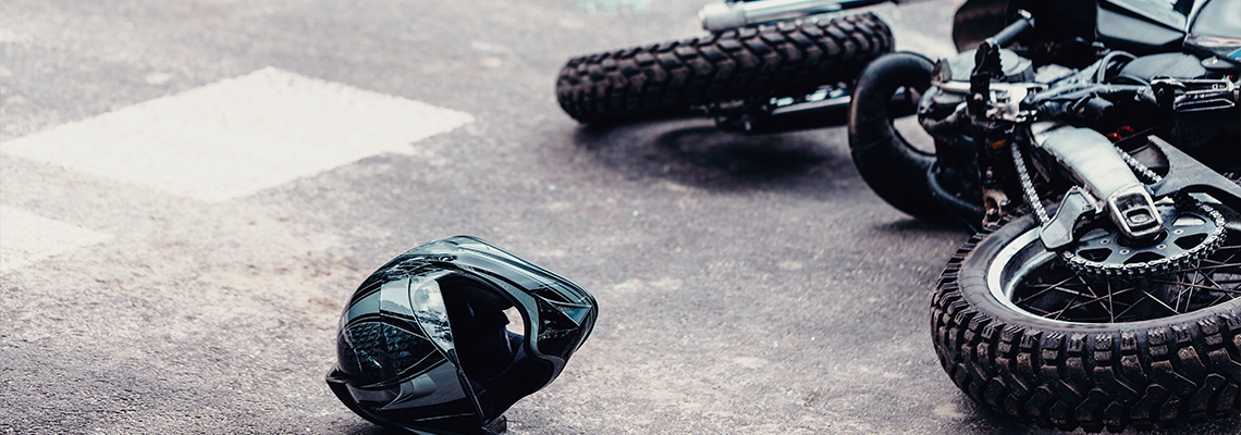 Helmet and motorcycle next to broken peaces of a car on the street after car crash