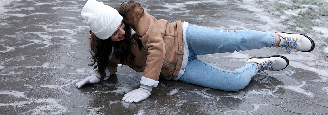 Young woman fallen on slippery icy pavement outdoors
