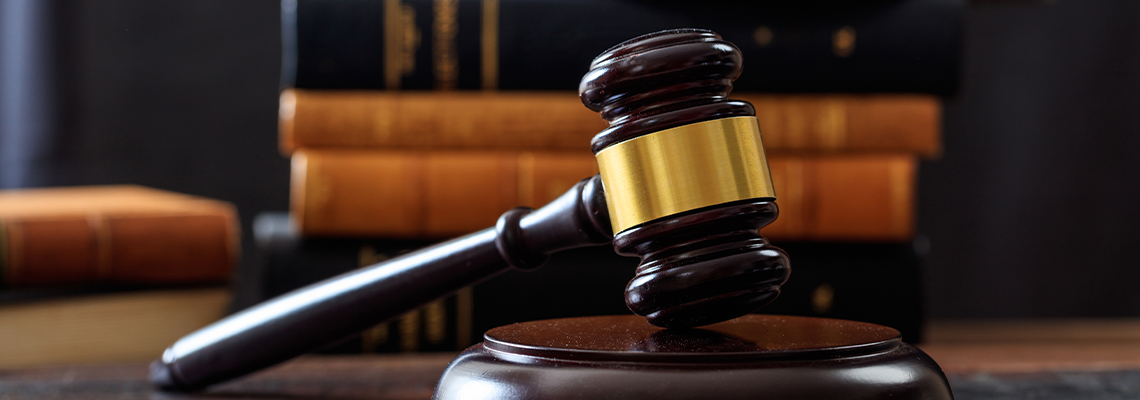 Judge gavel on a wooden desk, law books background