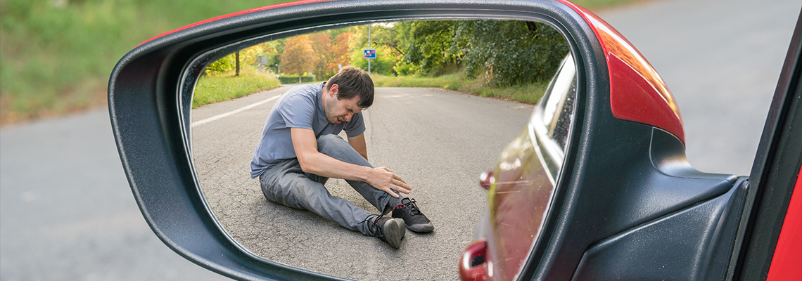 View on injured man on road in rear mirror of a car