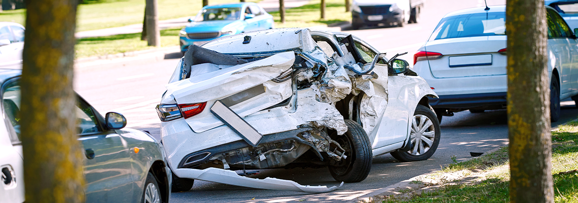 Parked car with fatal damage, completely wrecked frame sits roadside