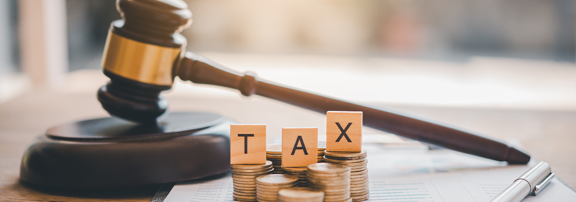 Wooden blocks word ' TAX' on coin stack .with gavel and money on the table