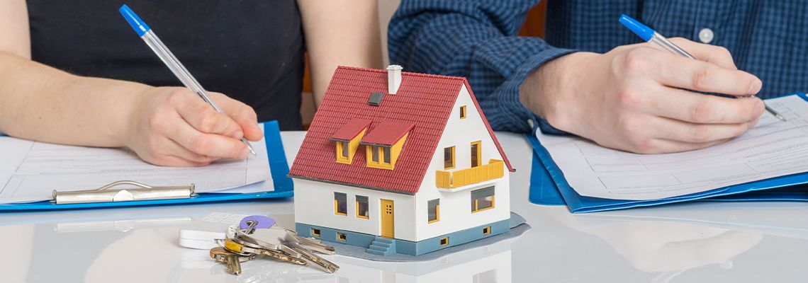 Couples signing divorce paper with house model in front of them