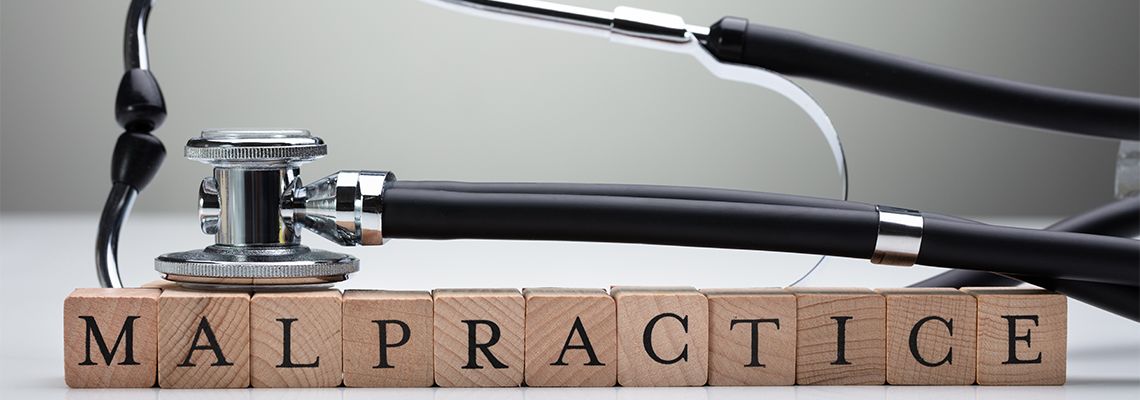 Stethoscope Over Malpractice Wooden Block