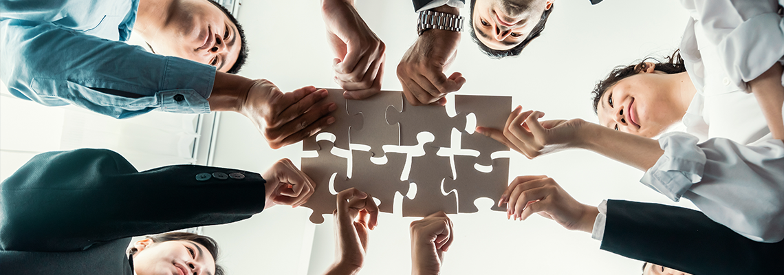 Business people holding jigsaw pieces and merge them together