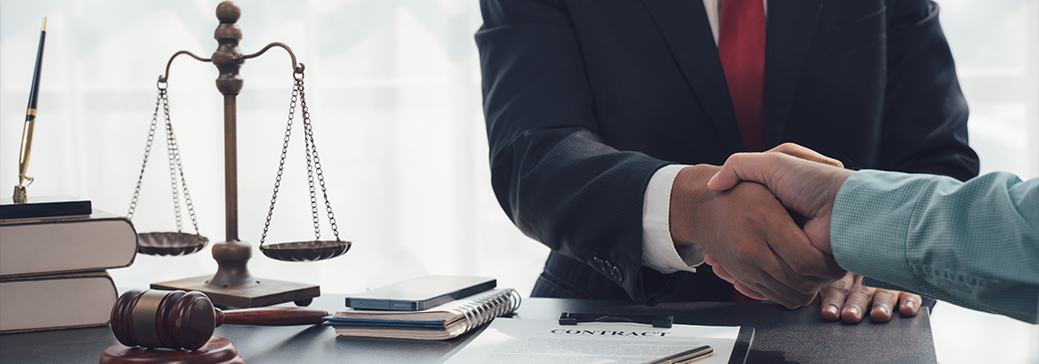 A lawyer in a crisp suit and red tie extends his hand for a handshake with a client