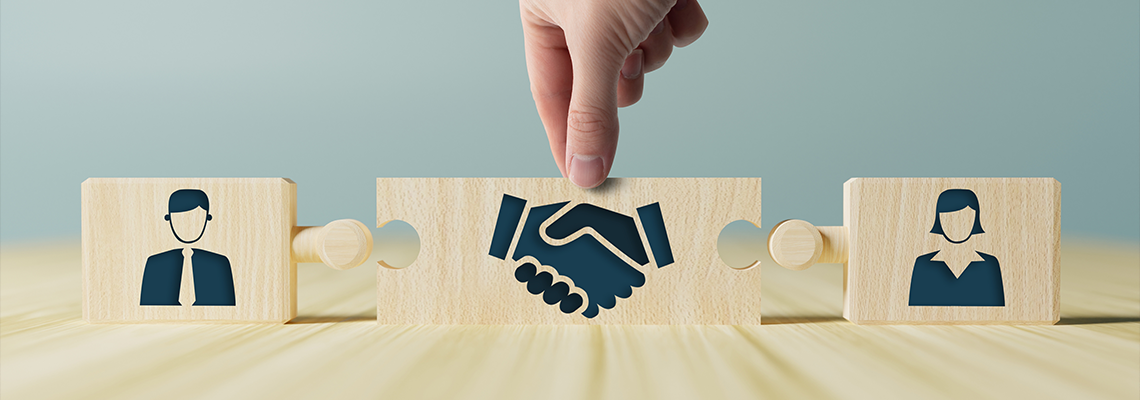 Wooden blocks with icons of a woman and a man and shaking hands