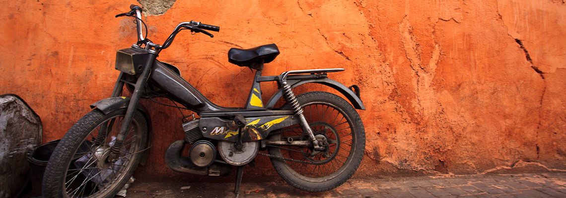 Old moped against orange wall