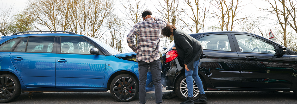 Young Male And Female Drivers Getting Out Of Cars And Inspecting Damage