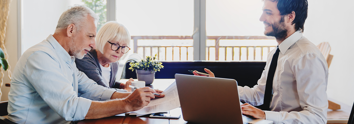 Senior couple planning their investments with financial advisor in living room at home