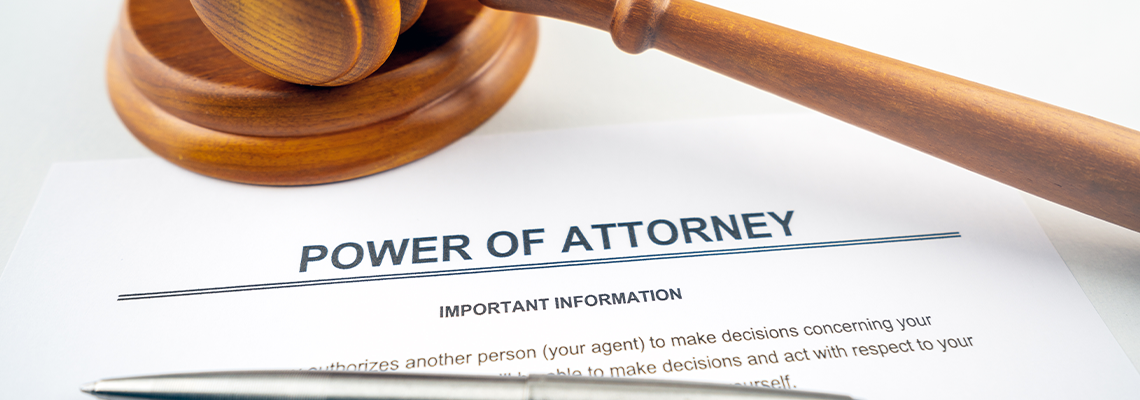 Power of attorney text on contract with pen, gavel and glasses as props