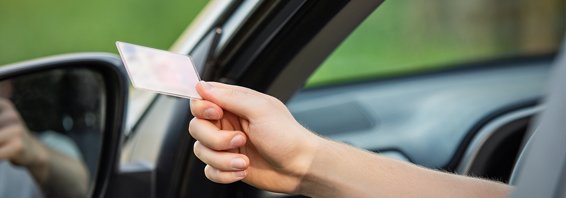 Close up person hand out of the car window holding the driver license