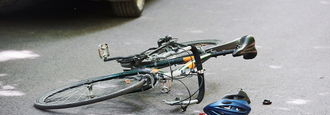 Bicycle and silver colored car accident on the road at forest at daytime