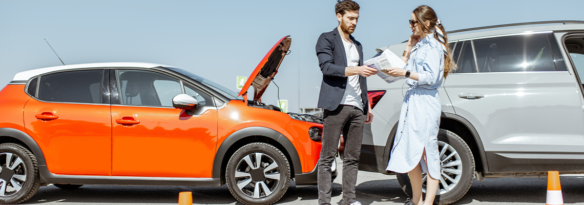 Man and woman arguing, standing together on the road with their cars on the background