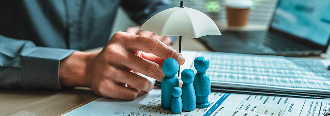 A wooden doll under an umbrella holding by agent represent insurance