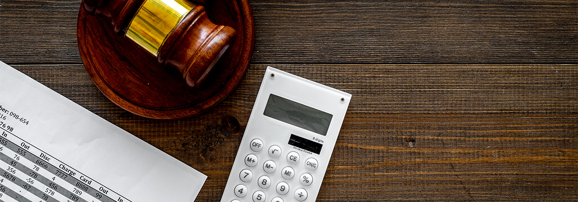 Judge gavel, financial documents, calculator on dark wooden background