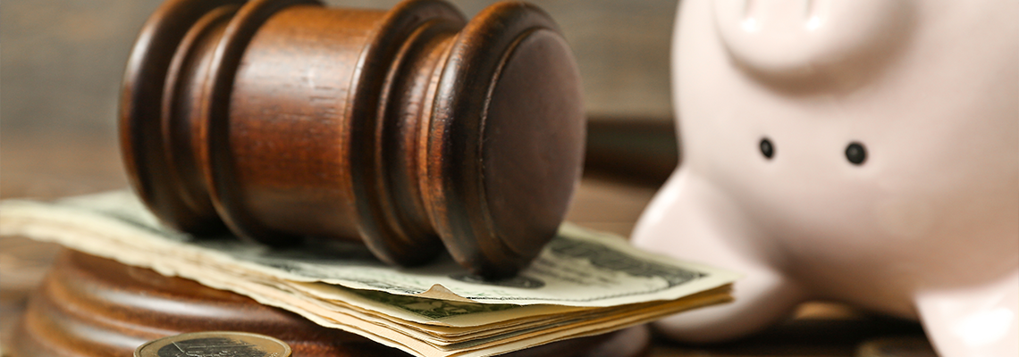 Piggy bank with judge gavel and money on brown wooden background