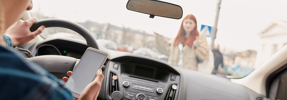 Young male driver looking at the screen of his mobile phone while driving