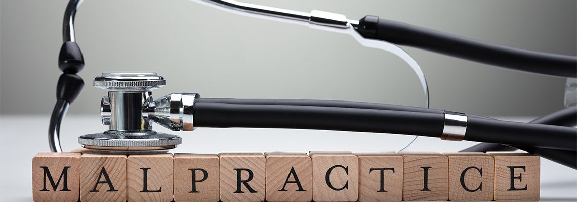 Stethoscope Over Malpractice Wooden Block
